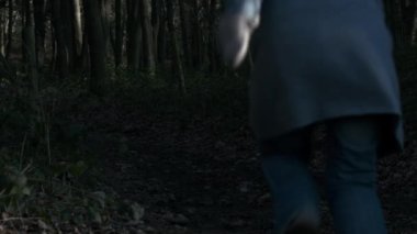 Karanlık ormanlık alanda koşan korkmuş bir kadın. 4K yavaş çekim seçici odaklanma.