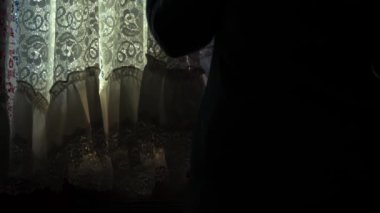 Anxious woman looking through net curtains medium shot slow motion 4k selective focus