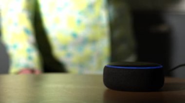 Home smart voice device in home with woman dancing in background 4k shot selective focus