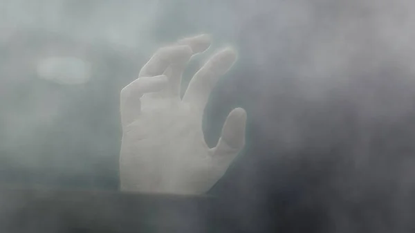 Hand at window surrounded by smoke close up selective focus