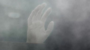 Hand at window surrounded by smoke close up slow motion 4k selective focus