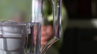 Water filter jug with woman exercising in background medium shot slow motion4k selective focus