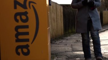 Customer using Amazon collection locker point in street wide zoom slow motion shot selective focus Dewsbury West Yorkshire UK 24th December 2022