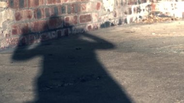 Shadow of woman putting hood up on coat brick background medium shot selective focus