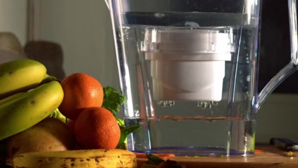 新鮮な水と果物の中でキッチンでのウォーターフィルタージャグは スローモーションズーム選択的フォーカスを撮影 — ストック動画
