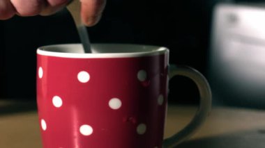 Stirring mug of hot coffee in colorful mug close up shot slow motion 4k selective focus