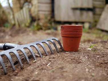 Garden rake and plant pots in a garden medium shot selective focus