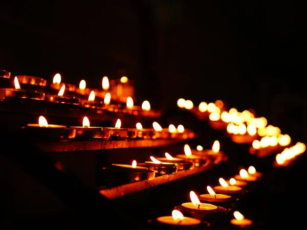 Rows of tea light candles burning in a church wide shot selective focus