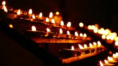 Kilise genelinde yanan çaylı mumlar yavaş çekimde seçici odaklanma görüntüsü verir.
