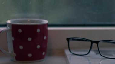 Sıcak içecek ve kitap yağmurlu bir günde pencerede yakın çekim yavaş çekim seçici odak