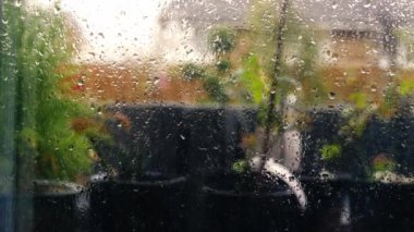 Bahçeye bakan penceredeki yağmur damlaları yavaş çekimde seçici odak 