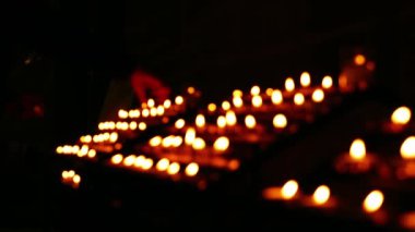 Sıralar dolusu çay ışığı mumları kilise çapında yavaş çekimde yanıyor seçici bir odak noktası.