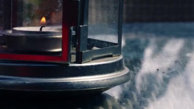 Işıklı mum alevi bir fenerde yanıp sönüyor. 4k 'lık çekimde seçici bir odak noktası var.