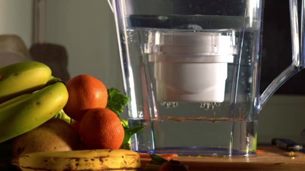 ウォーターフィルタージャグでキッチンで新鮮な水とフルーツ中出しスローモーション4K選択的フォーカス — ストック動画