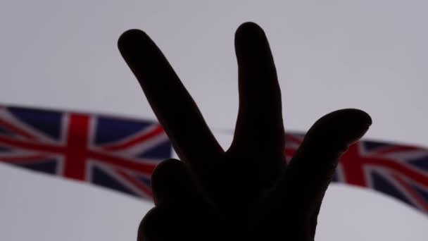 Ręce Pokazujące Znak Zwycięstwa Sylwetką Tła Flagi Union Jack Zbliżenie — Wideo stockowe