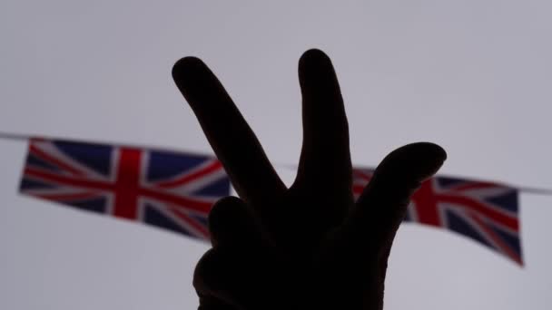 展示胜利标志的手与欧盟杰克旗的轮廓背景接近4K选择焦点 — 图库视频影像