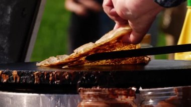 Krep fırınındaki panayırda çikolata soslu krep yapmak. 4K seçici odak noktası.