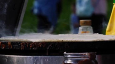 Krep fırınındaki panayırda çikolata soslu krep yapmak. 4K seçici odak noktası.