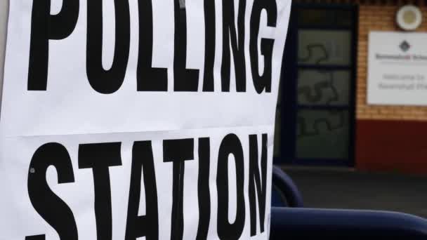 風の中で英国の投票所のサインを閉じるショットズームスローモーション選択的フォーカス — ストック動画