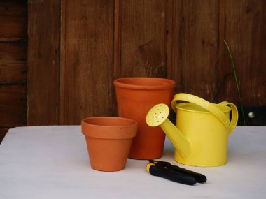 Sarı sulama kutusu ve arka plandaki terracotta saksıları seçici odak noktası