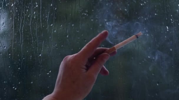 Mãos Fumante Frente Janela Como Chuva Cai Fora Escuro Dia — Vídeo de Stock