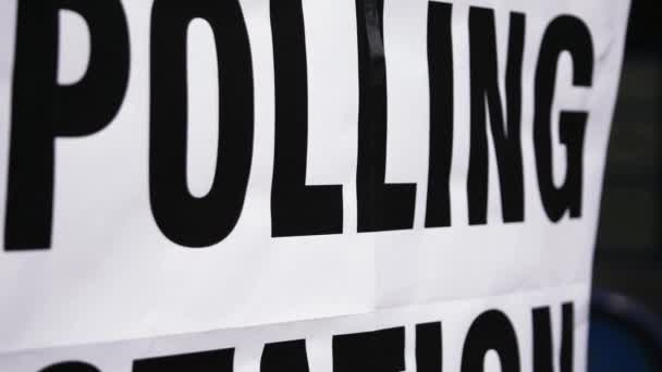 風の中で英国の投票所のサインを閉じる傾斜ショットズームスローモーション選択的フォーカス — ストック動画
