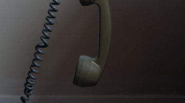 Klasik döner telefon alıcısı. Orta yavaş çekimde asılı. 4k eğik odak noktası.