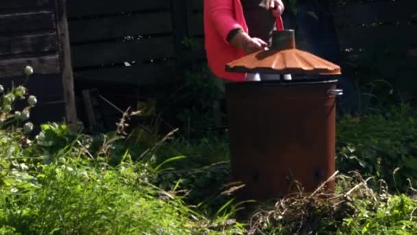 ゴミの広いショットのズーム遅い動きの選択的な焦点を処分するためにビン焼却器を使用する女性 — ストック動画