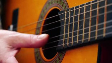 Müzisyen akustik gitar çalıyor. Yakın çekim, yavaş çekim zoom, seçici odaklanma.