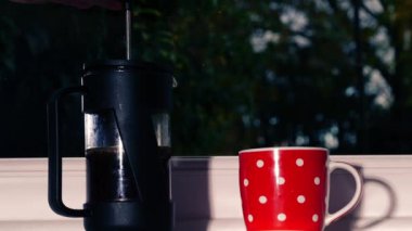 Cafetiere 'de, pencerede taze kahve yapmak. Orta boy, yavaş çekim, zoom seçici odaklanma.