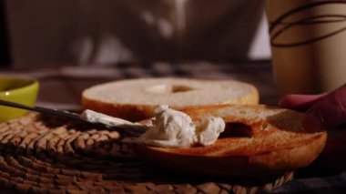Dilimlenmiş ve krem peynirle kızartılmış bagel ekmeği sunarken orta boy zoom yavaş çekim seçici odak noktası
