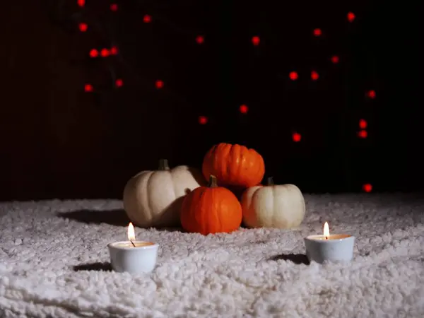 Sıcak arka planda mumları olan sonbahar balkabakları geniş açılı seçici odak noktası