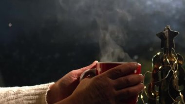 Noel ortamında pencerenin önünde sıcak içecek yavaş çekimde seçici odak
