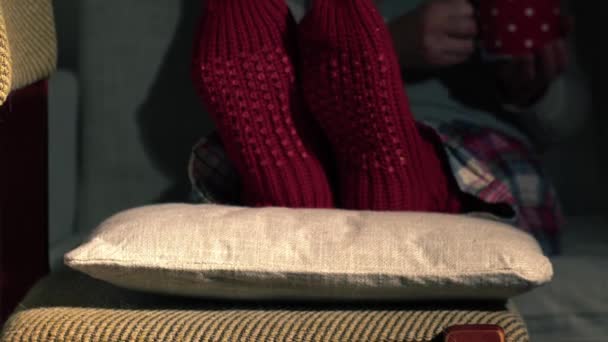 Женщина Кладет Ноги Уютные Рождественские Носки Чашкой Кофе Среднего Замедленной — стоковое видео
