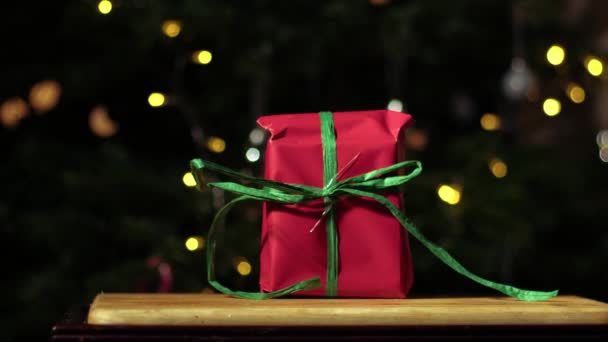 赤と緑のお祝いのボケの背景に包まれたクリスマスギフト 中型4K人形選択的な焦点 — ストック動画