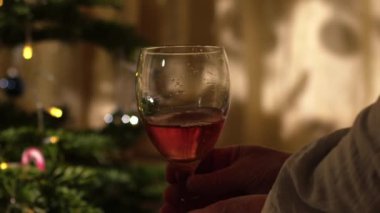 Noel ağacının önünde bir kadeh kırmızı şarapla rahatlayan bir kadın. Yaklaş, odaklan, odaklan.