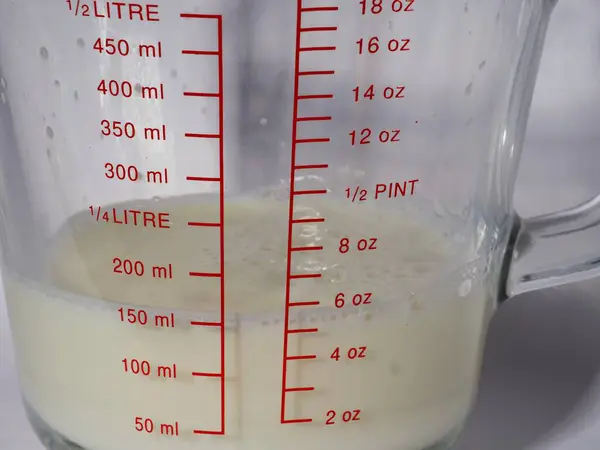 Jug of milk in glass measuring jug white background close up shot selective focus
