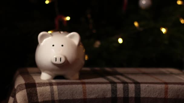 クリスマスツリーバックグラウンドのピギーバンク貯蓄 中型人形ズームショット選択的な焦点 — ストック動画