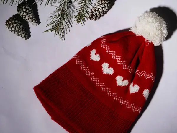 Kış kozalakları ve beyaz arka planda kırmızı örülmüş şapkalar orta boy seçici odak noktasında yatıyordu.