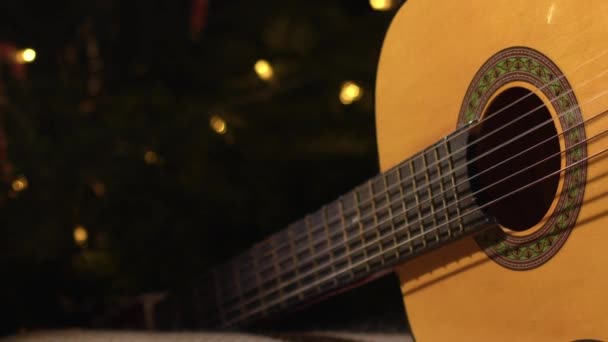 クリスマスツリーの前で音響ギター 中型ズーム人形ショット選択的な焦点 — ストック動画