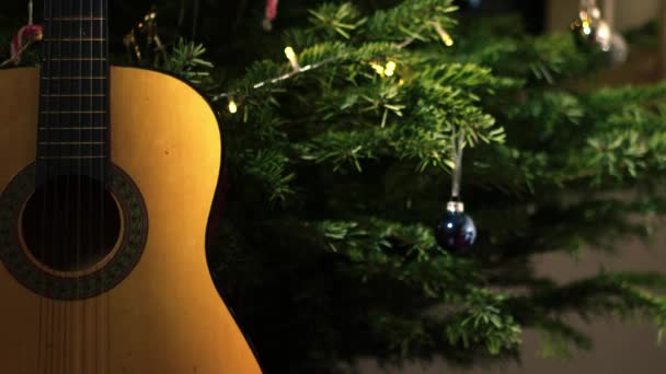 クリスマスツリーの前にアコースティックギター 中型の人形4Kショット選択的な焦点 — ストック動画