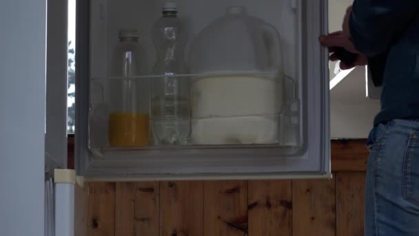 女性は冷蔵庫媒体4Kショット選択的な焦点から新鮮なオレンジジュースを得る — ストック動画