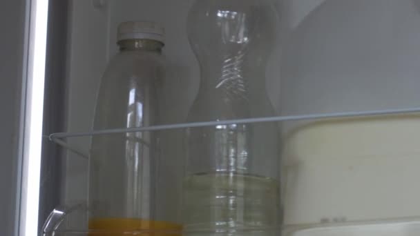 女性は冷蔵庫から新鮮なオレンジジュースを得る ズームショット選択的な焦点を閉じる — ストック動画