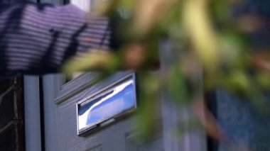 Kadın evin ön kapısına gidiyor. 4K orta boy, seçici odak noktası.