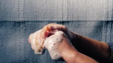 Kadın ellerini sabunlu köpüklerle yıkıyor ve su yavaşça kapanıyor. 4k seçici odaklanma. 