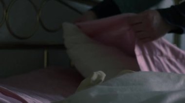 Yatakta pembe yastıkları kabartan kadın. Orta boy, yavaş çekim seçici odaklanma.