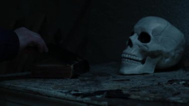 Yıldırım fırtınasında insan kafatası olan ürkütücü, eski bir kitap. Seçici bir odak noktası.