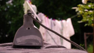 Buhar ütüsü ve çamaşır makinesi arka planda asılı. Yakın çekim odaklı.