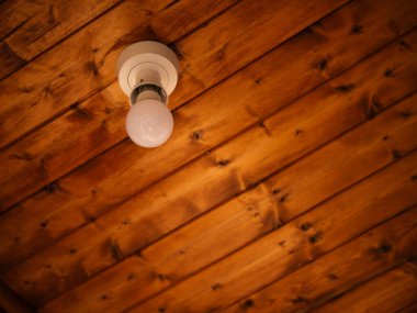 Tahta tavan ortasındaki elektrik ampulü seçici odak noktası