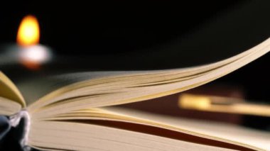 Sayfalar mum ışığı arkaplanı bokeh olan açık bir kitap açar yakınlaştırma çekimini seçici bir odak ile kapatır